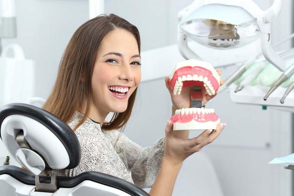 Девушка в стоматологическом кресле с челюстью в руках