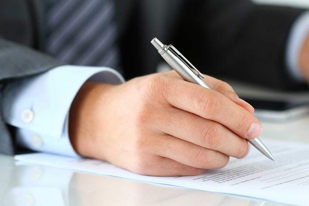 Ручка в руке возле документа